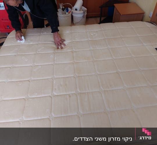 אדם מנקה מזרן עם מטלית לבנה